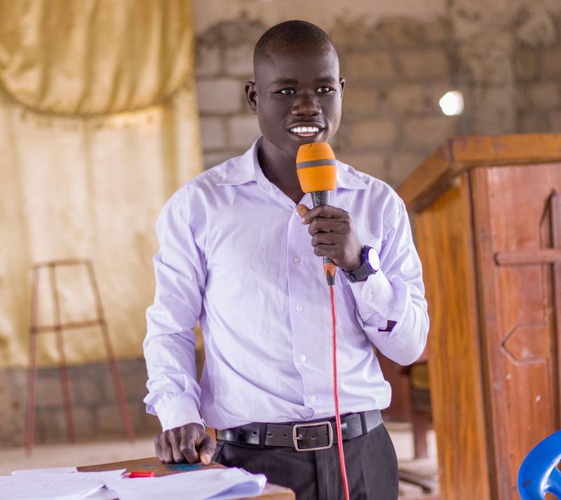 A secondary school student in a lilac shirt gives a speech into a microphone at a schools contest